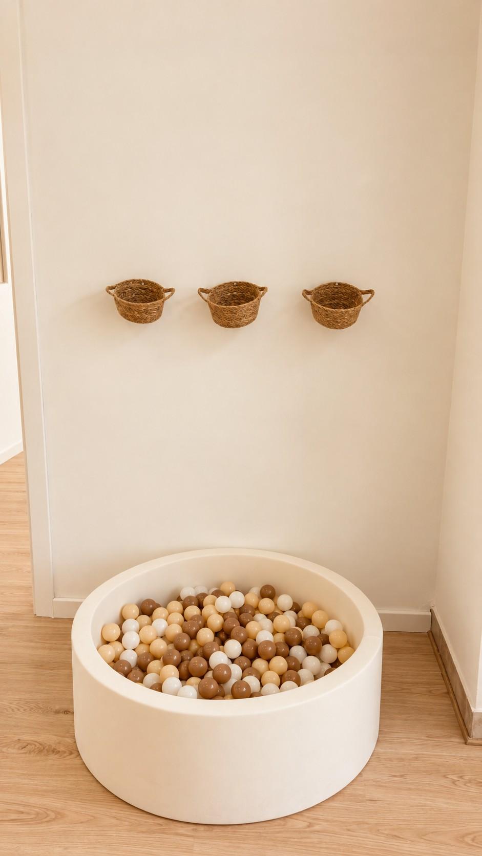 Piscina de bolas en tonos naturales junto a cestitas colgadas